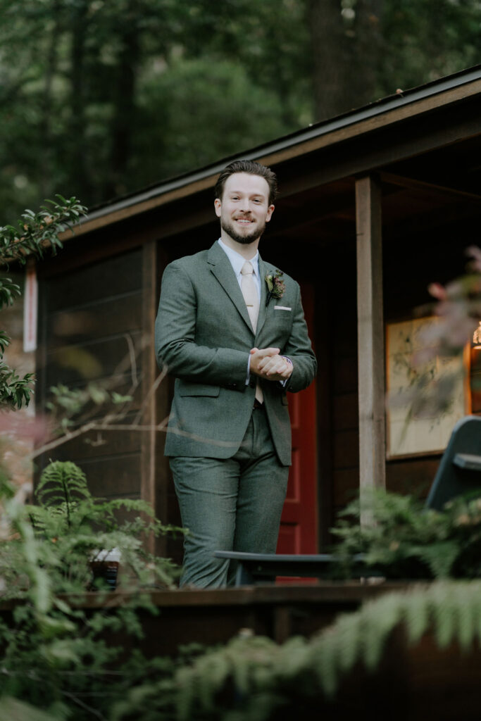 groom getting ready in front of a rustic cabin