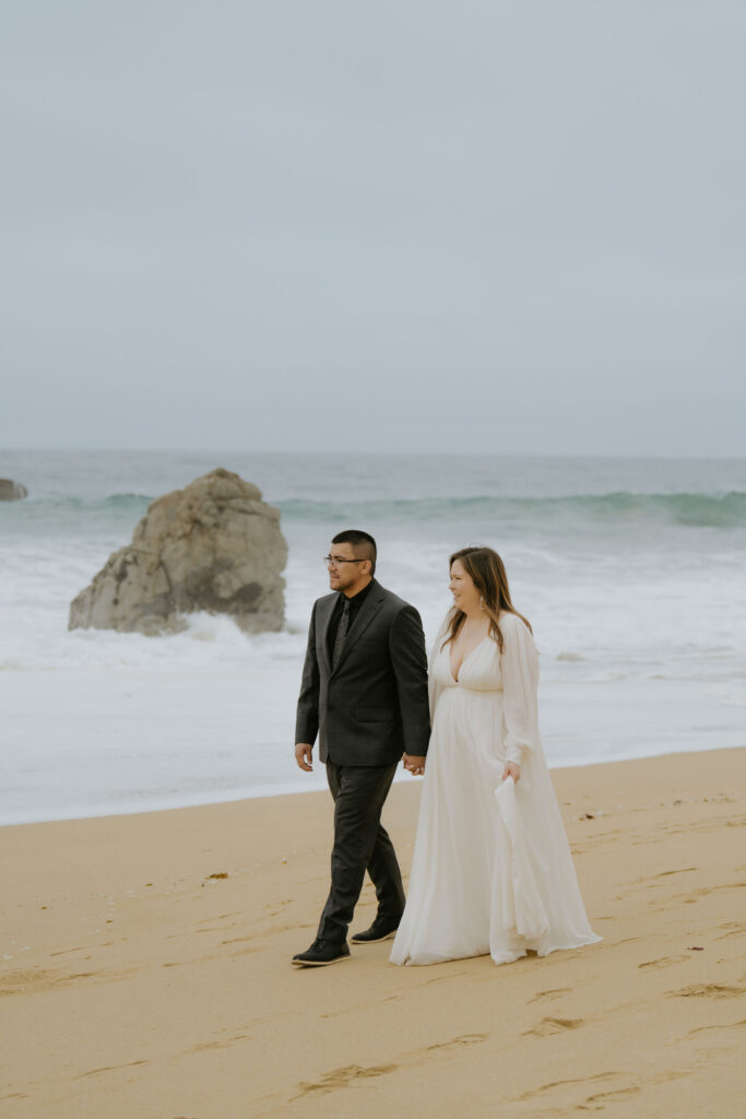 cute picture of the bride and groom walking around the beach