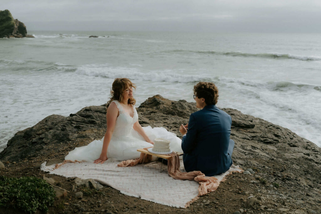 eloping couple sharing wedding cake on the beach