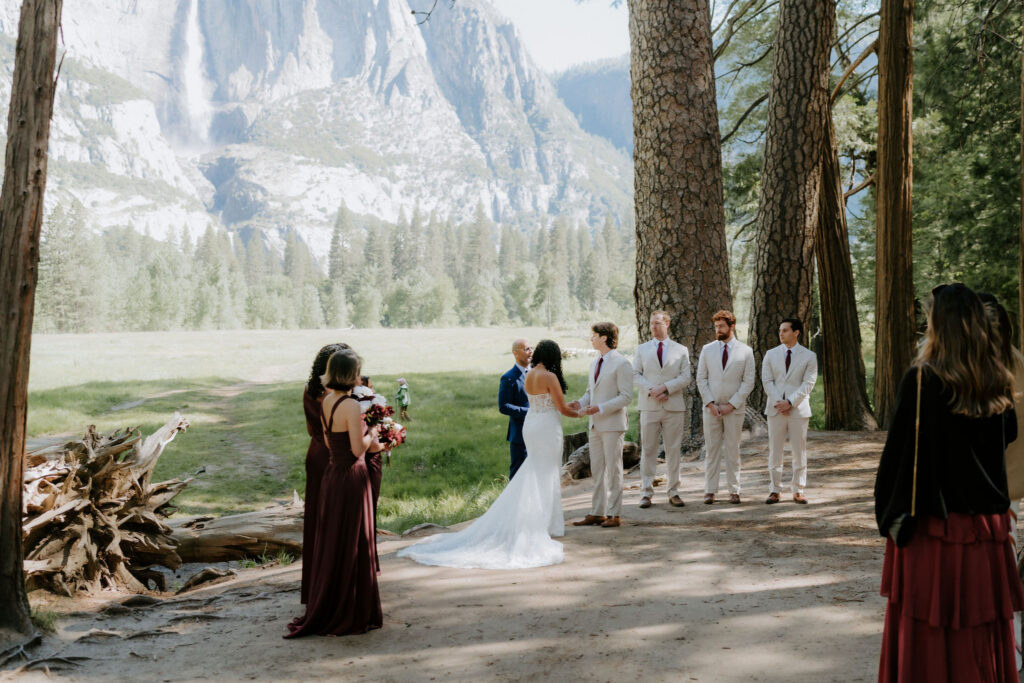bride and groom holding hands during their wedding ceremony at swinging bridge in yosemite
