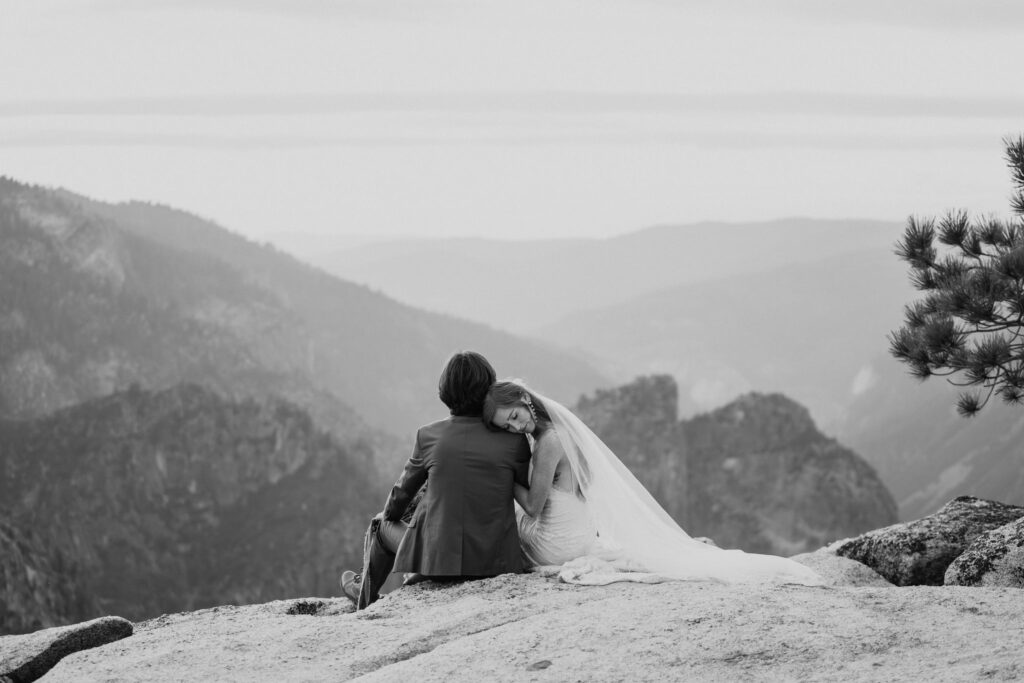 black and white couple sitting on cliff edge taft point
