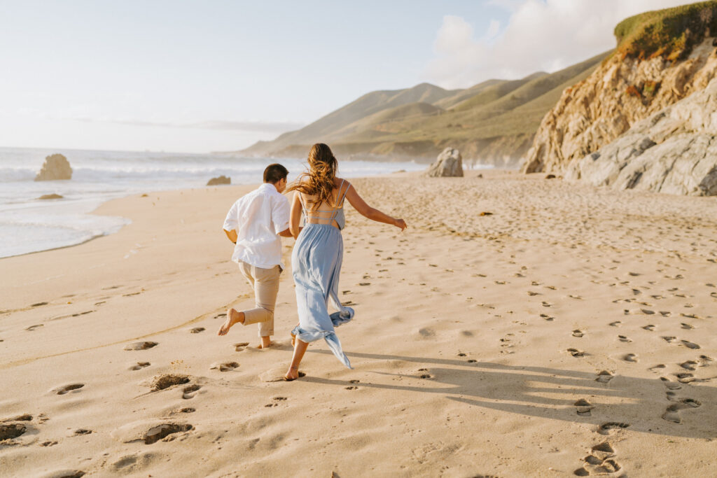 couple running on beach at big sur